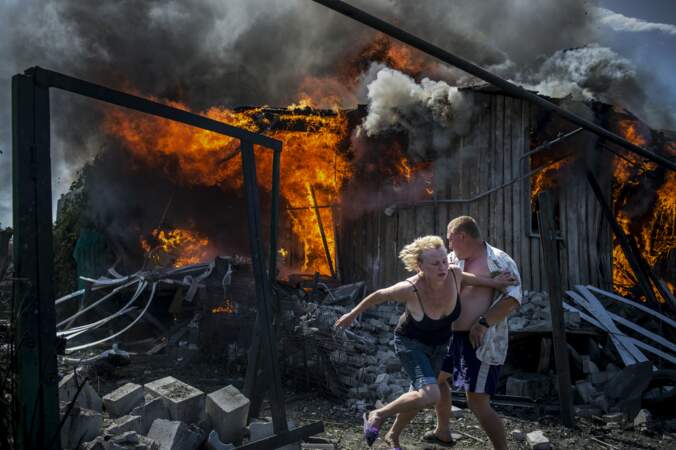 2 juillet 2014,Luhanskaya, Ukraine. Civils fuyant un village incendié après une attaque aérienne.