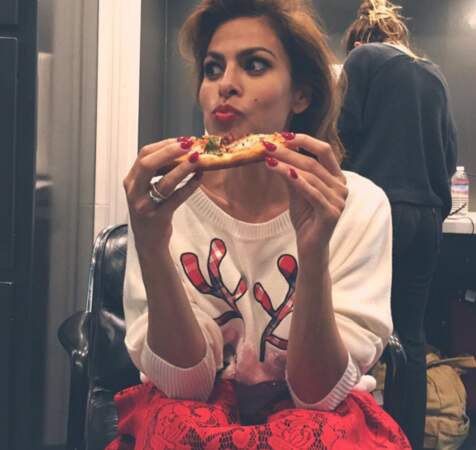 Eva Mendes mange une part de pizza dans son pull de Noël