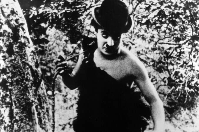 Charlie Chapin rêve qu'il est plongé en pleine Pré-histoire dans Charlot nudiste (1914)