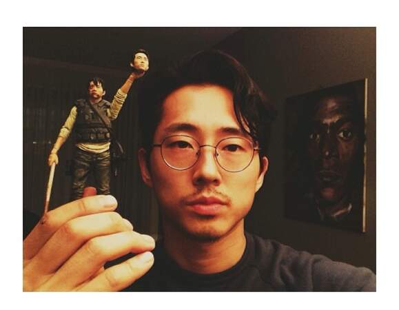 Steven Yeun tenant une figurine de Glenn brandissant la tête de Steven Yeun. Glauque, mais fun !