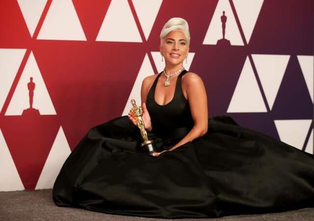 Lady Gaga reçoit l'Oscar pour la chanson du film "A star is born" habillée d'une robe noire signée Alexander McQueen. Elle porte le même collier de diamants de chez Tiffany's que portait Audrey Hepburn en 1961. Sa valeur est estimée à de 30 millions de dollars ! 