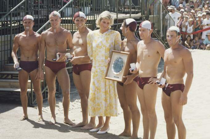 La princesse de Galles pose avec un groupe de sauveteurs au Terrigal Beach Surf Carnival Australie, en janvier 1988. Elle porte une robe jaune et blanche de Paul Costelloe.