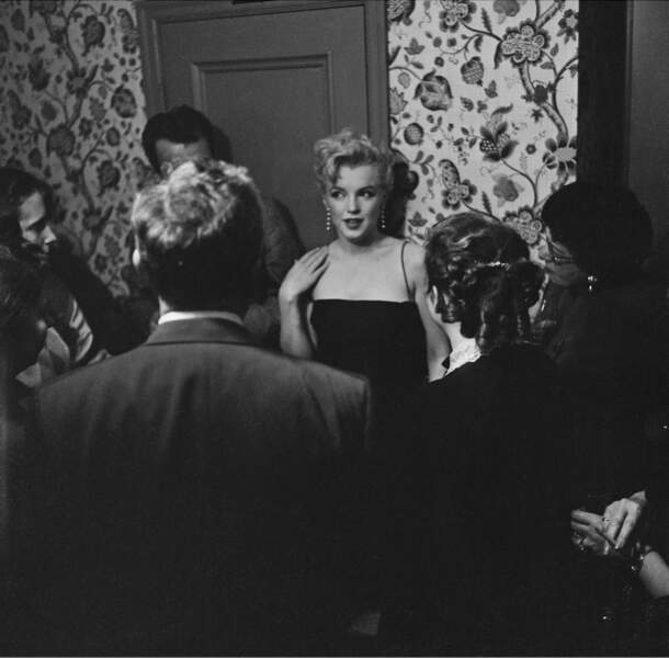 En contraste avec l'air sérieux des invités et la sobriété de l'intérieur, Monroe apporte à cette scène une certaine touche de glamour, bien qu'à cette date en 1951, elle n'ait pas encore eu de rôle principal dans un film.