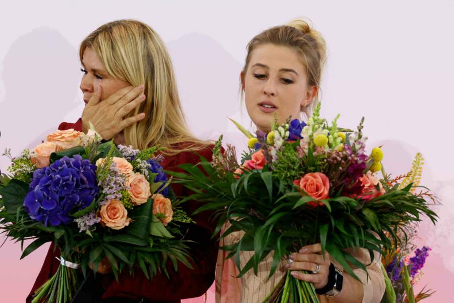 La femme de l'ancien sportif essuie ses larmes en même temps qu'elle récupère ce beau bouquet.