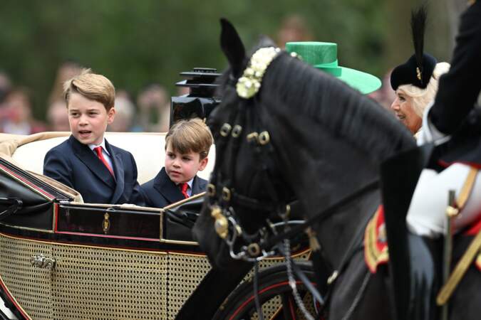 Le Prince George et le Prince Louis, en calèche, élégants en costumes sombres et cravates rouges.