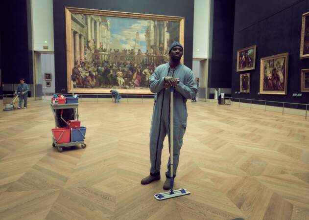 Assane Diop a visité l'un des plus grands musées du monde : Le Louvre. Ici, on peut le voir en arrière-plan le tableau des noces de Cana réalisé par le peintre Paul Véronèse en 1953.
